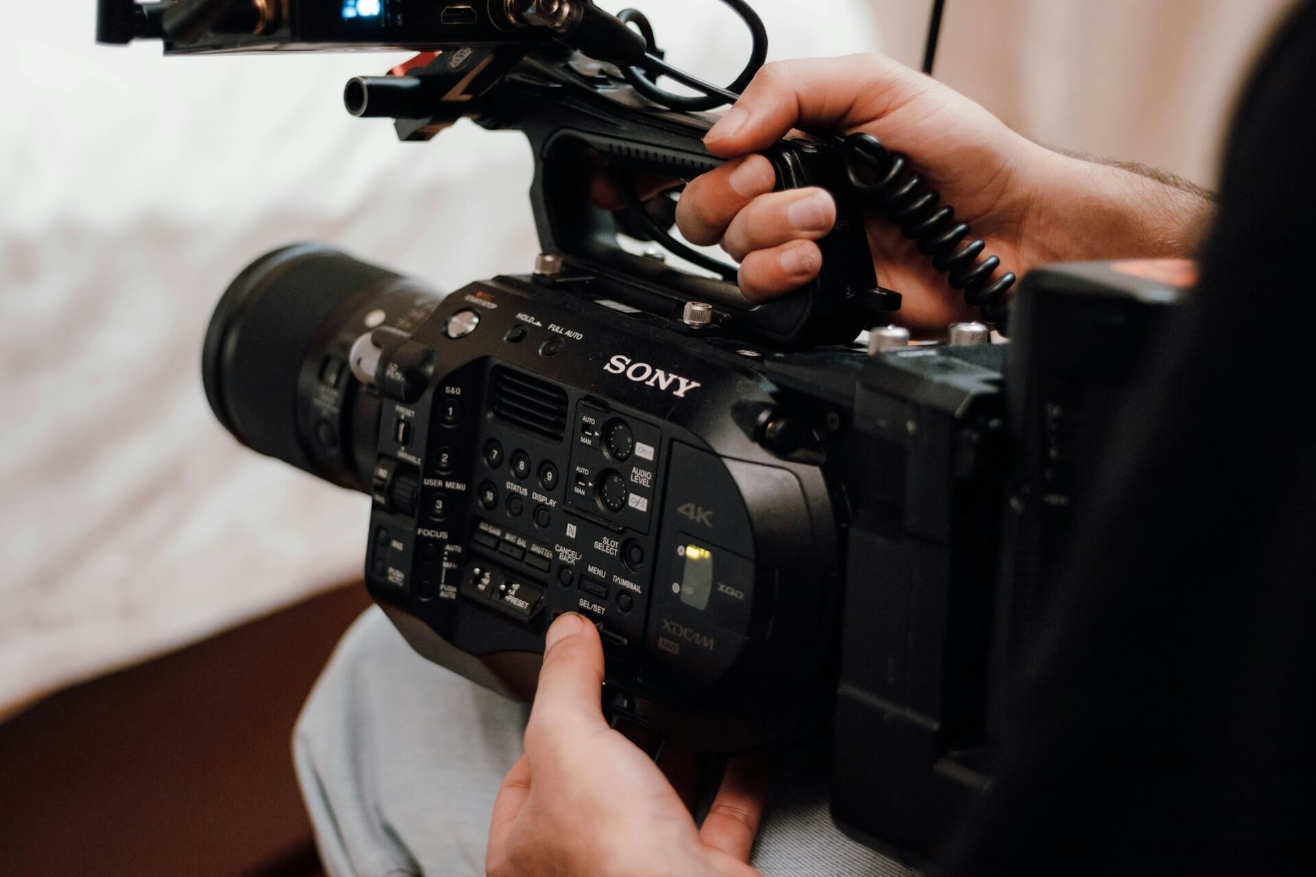 Close-up of a person holding and operating a Sony FX6 cinema camera.